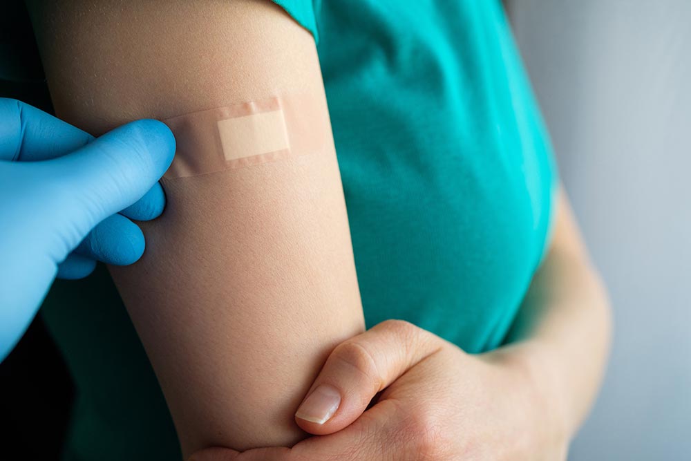 Läkareapplicerar plåster på en kvinnas arm efter vaccination